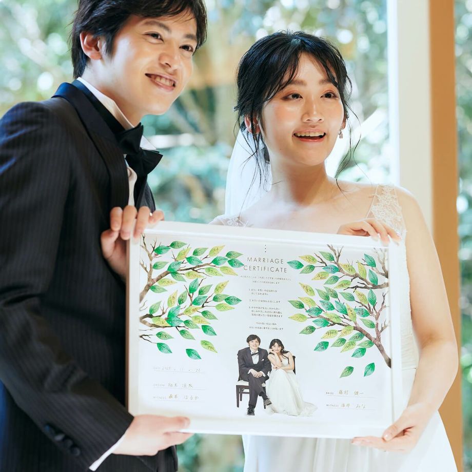 ナチュラルおしゃれなツリーデザインの結婚証明書をかかげる新郎新婦