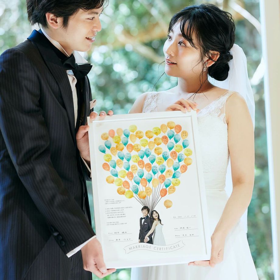 おしゃれキュートなバルーンデザインの結婚証明書をかかげる新郎新婦