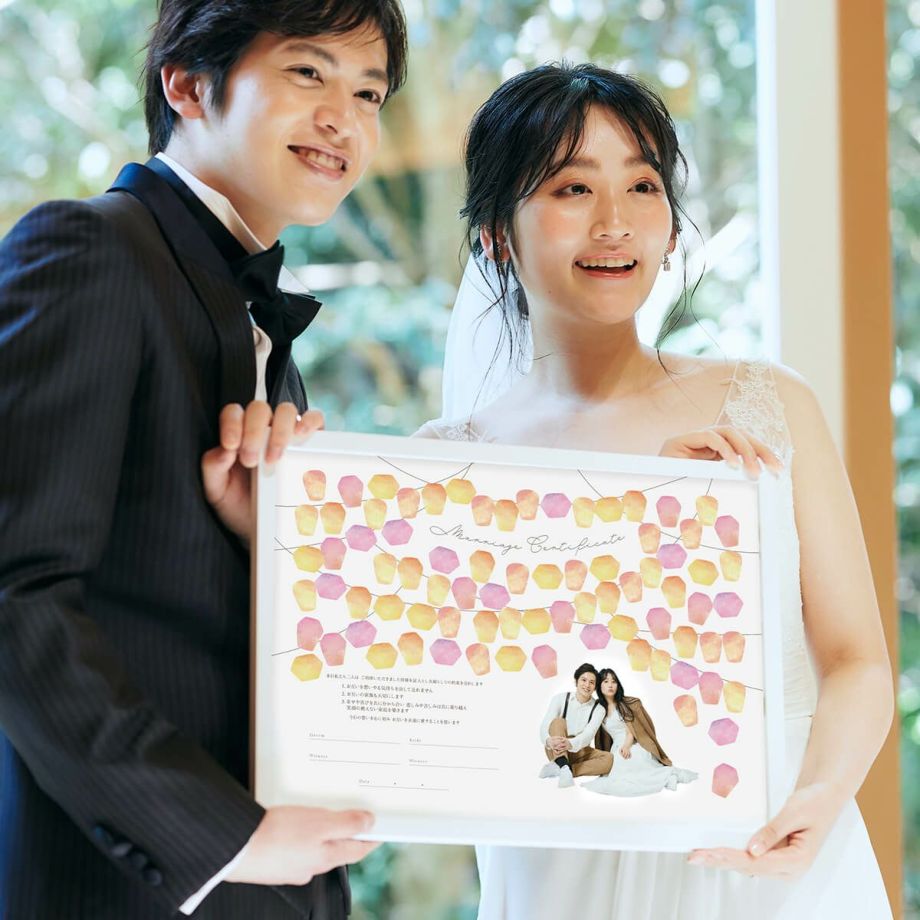 やさしく灯った無数のランタンをイメージしたデザインの結婚証明書をかかげる新郎新婦