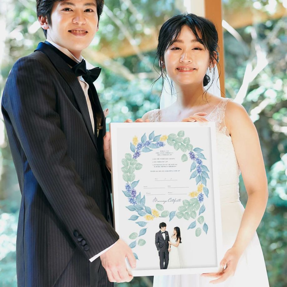 ナチュラルおしゃれなリースデザインの結婚証明書をかかげる新郎新婦