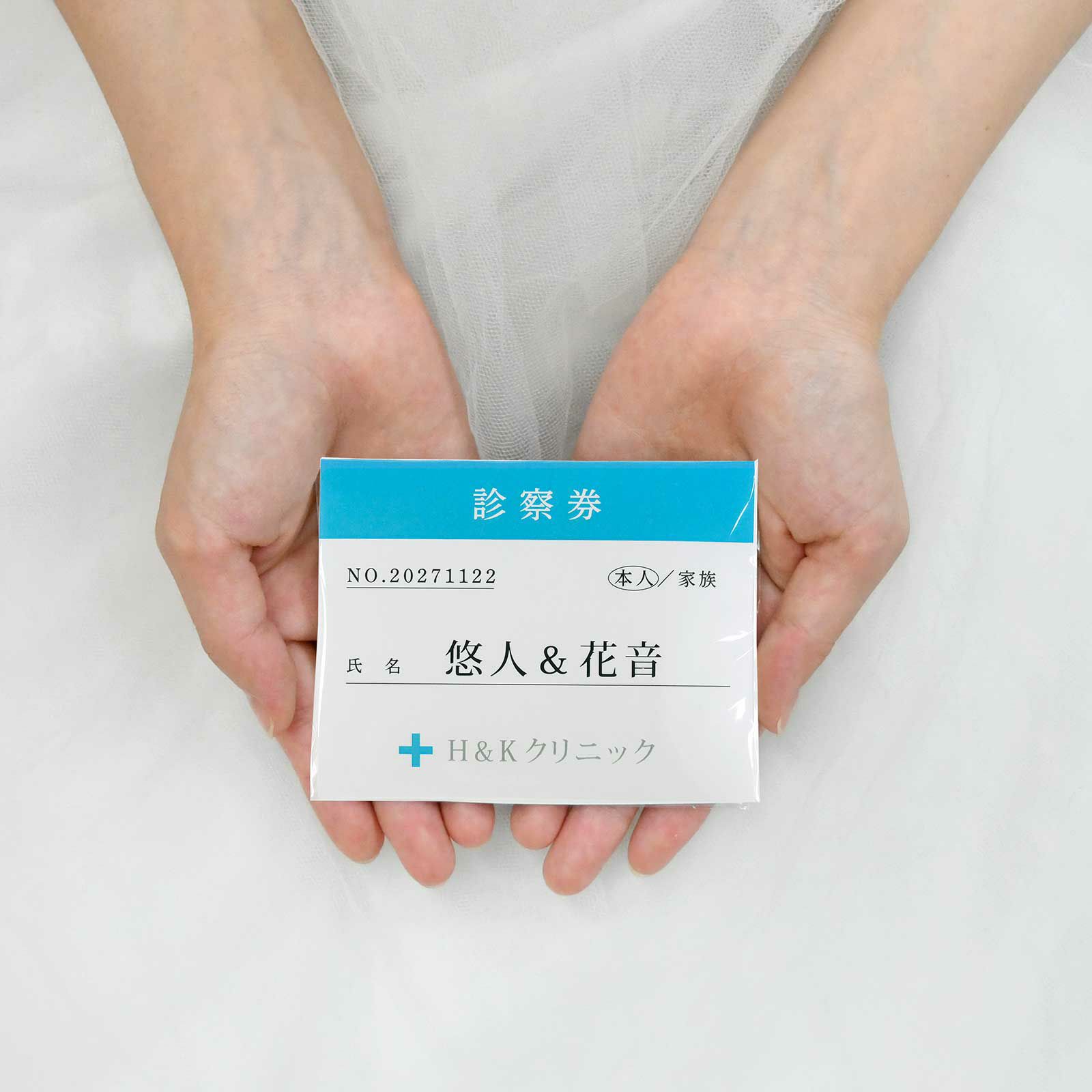 診察券にそっくりなデザインのプチギフトを手に持っている花嫁